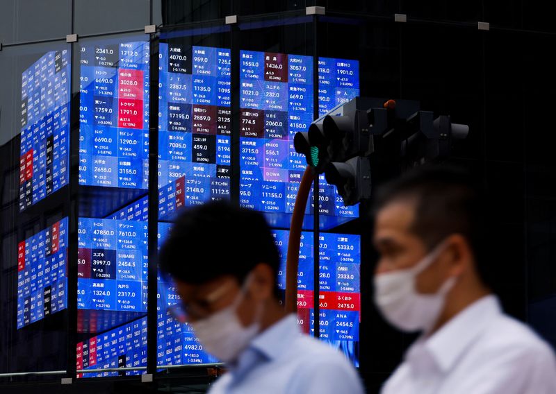 People pass by an electronic screen showing Japan's Nikkei share price index inside a conference hall  in Tokyo