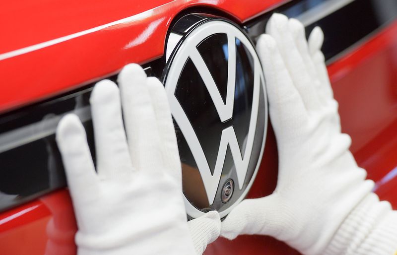 FILE PHOTO: A technician attaches a Volkswagen logo to a car, at the production line for electric car models of the Volkswagen Group, in Zwickau