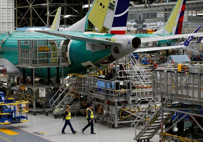 FILE PHOTO: Employees walk by the end of a 737 Max aircraft at the Boeing factory in Renton