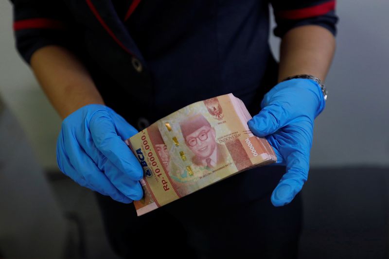 Employee wears synthetic gloves as she counts Indonesia's rupiah banknotes at a currency exchange office amid the spread of coronavirus disease (COVID-19) in Jakarta