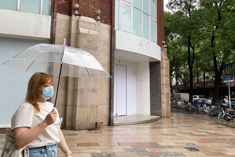 Woman walks past a closed H&M flagship store in Shanghai