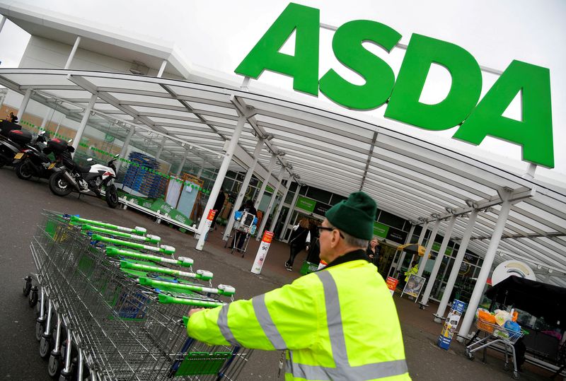 FILE PHOTO: A worker pushes shopping trolleys at an Asda store in West London, Britain