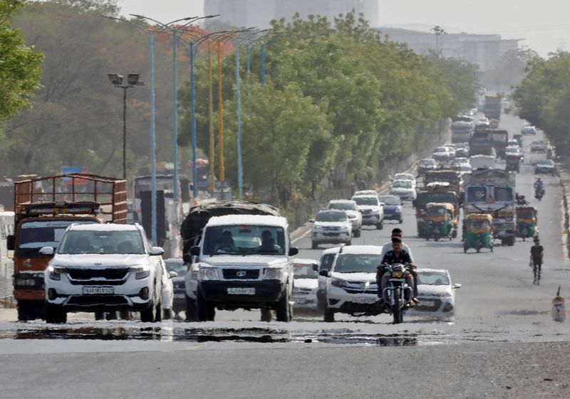FILE PHOTO: Traffic moves on a road in a heat haze during hot weather on the outskirts of Ahmedabad,