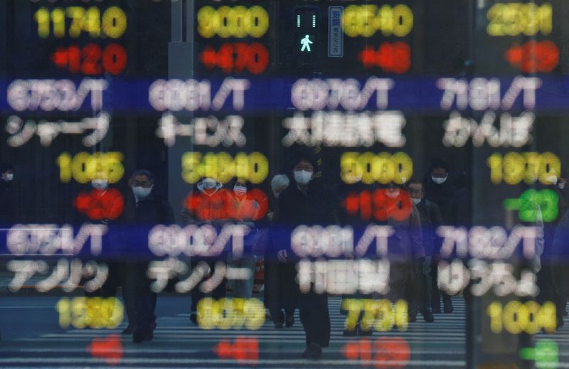 FILE PHOTO:  Pedestrians wearing protective masks are reflected on an electronic board outside a brokerage in Tokyo