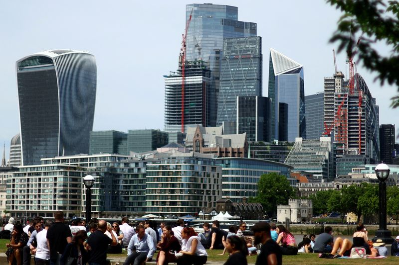 FILE PHOTO: People enjoy warm weather in front of the city of London financial district in London