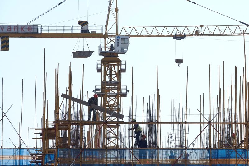 Vanke sign is seen above workers working at the construction site of a residential building in Dalian