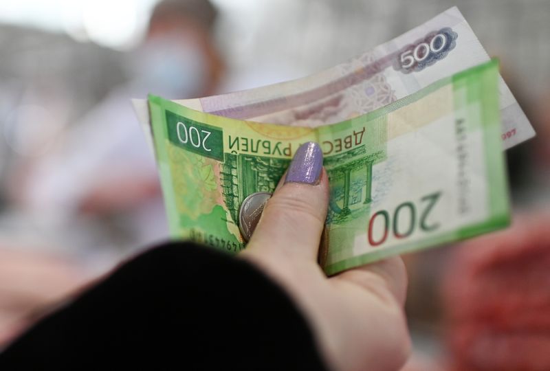 A customer hands over Russian rouble banknotes and coins to a vendor at a market in Omsk