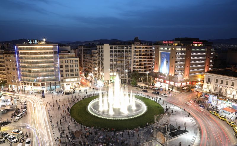 People gather around the fountain of the newly renovated Omonia square, in Athens