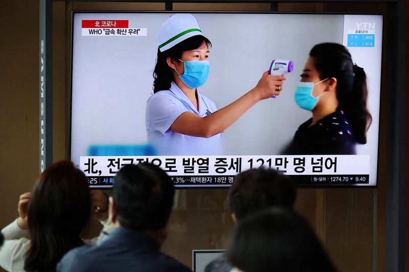 People watch a news report on the coronavirus disease (COVID-19) outbreak in North Korea