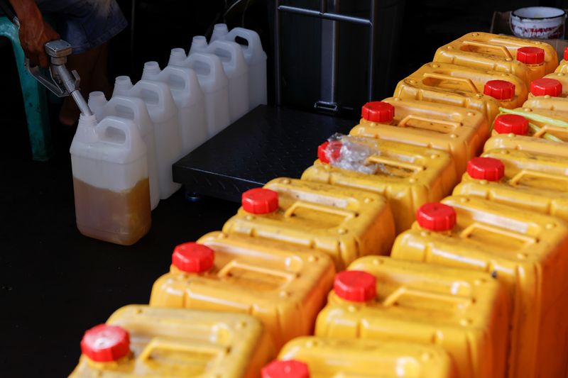 A worker fills jerrycans with cooking oil at a distribution station in Jakarta
