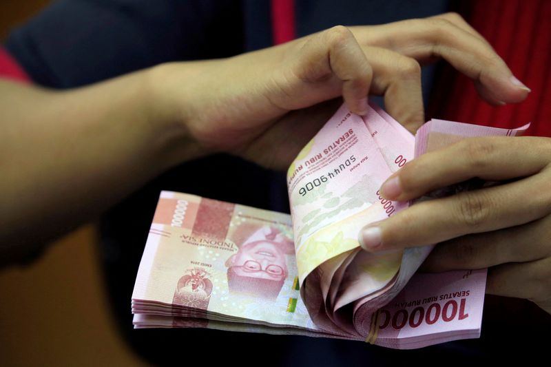FILE PHOTO: An employee counts Indonesian rupiah banknotes at a currency exchange office in Jakarta
