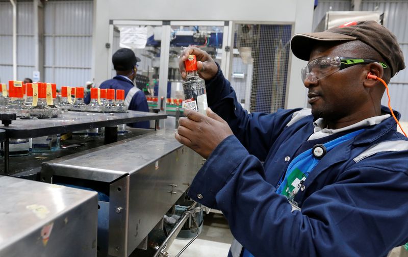 An employee inspects a bottle of Kenya Cane spirit from a conveyor belt at the East African Breweries Limited factory in Ruaraka factory in Nairobi
