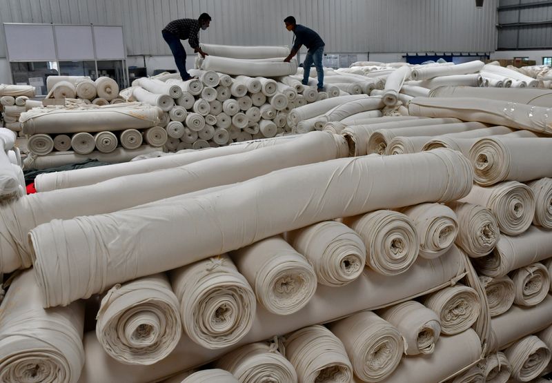 Workers stack cotton fabric rolls at a textile factory of Texport Industries in Hindupur