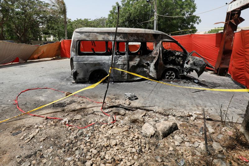 FILE PHOTO: A view of the crater and cordoned area near a damaged passenger van, a day after a suicide blast, at the entrance of the Confucius Institute University of Karachi