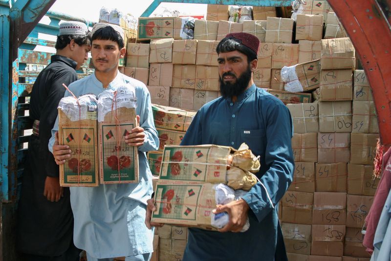 Labourers unload boxes of pomegranates from Afghanistan, from a truck at the 'Friendship Gate' crossing point, in the Pakistan-Afghanistan border town of Chaman