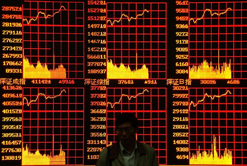 FILE PHOTO: A shareholder passes in front of a stock electronic board at a securities exchange in Shanghai May 9..