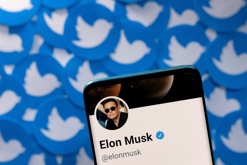 FOTO DE ARCHIVO: El perfil de Twitter de Elon Musk se ve en un teléfono colocado sobre logotipos impresos de Twitter
