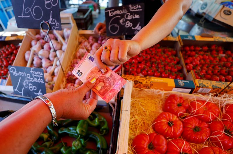 FILE PHOTO: A shopper pays with a ten Euro bank note at a local market in Nice