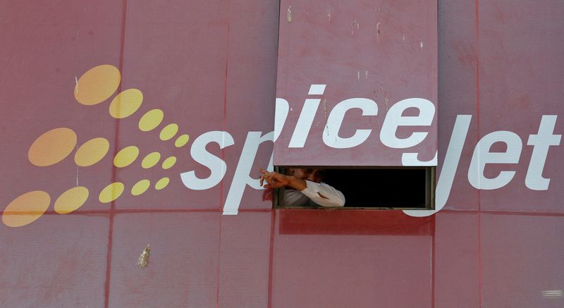 FILE PHOTO: Man looks out through a window with an advertisement of SpiceJet Airline, on a commercial building in the western Indian city of Ahmedabad