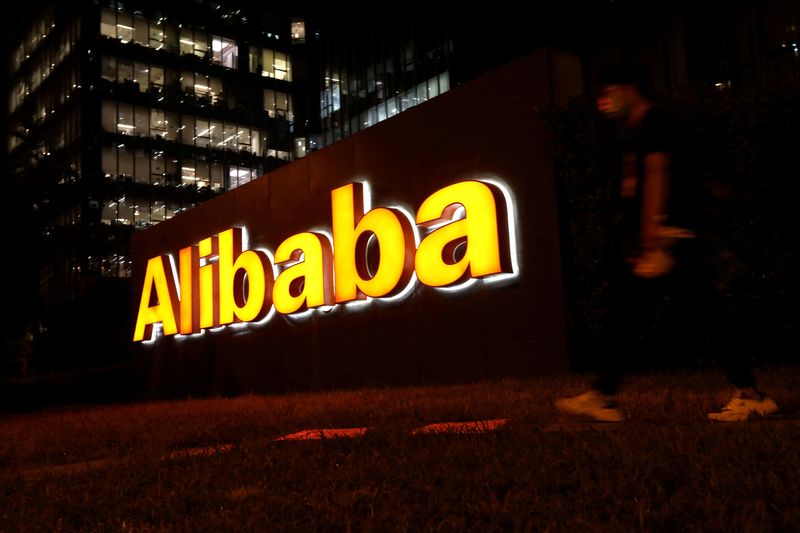 FILE PHOTO: Man walks past a logo of Alibaba Group at its office building in Beijing