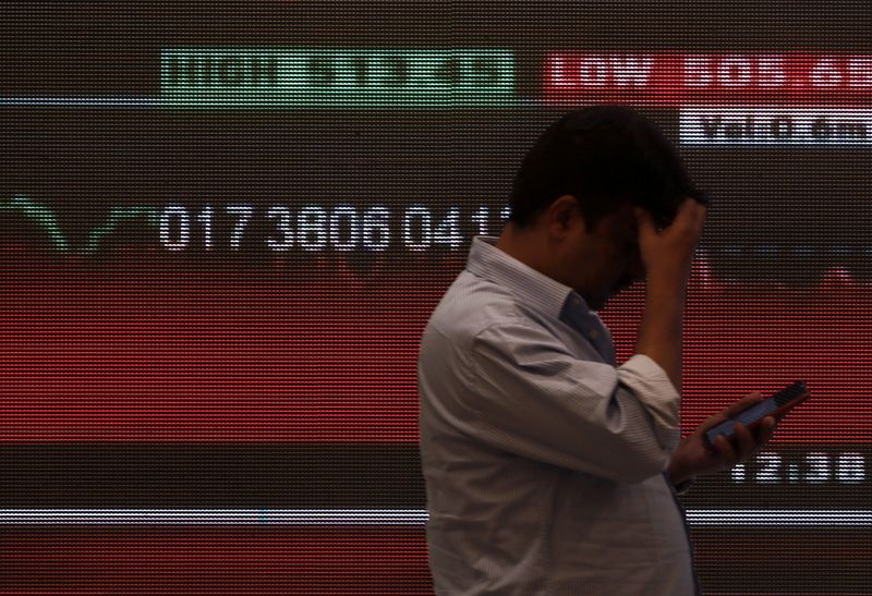 FILE PHOTO: A man stands in front of a screen displaying news of markets updates inside the Bombay Stock Exchange (BSE) building in Mumbai