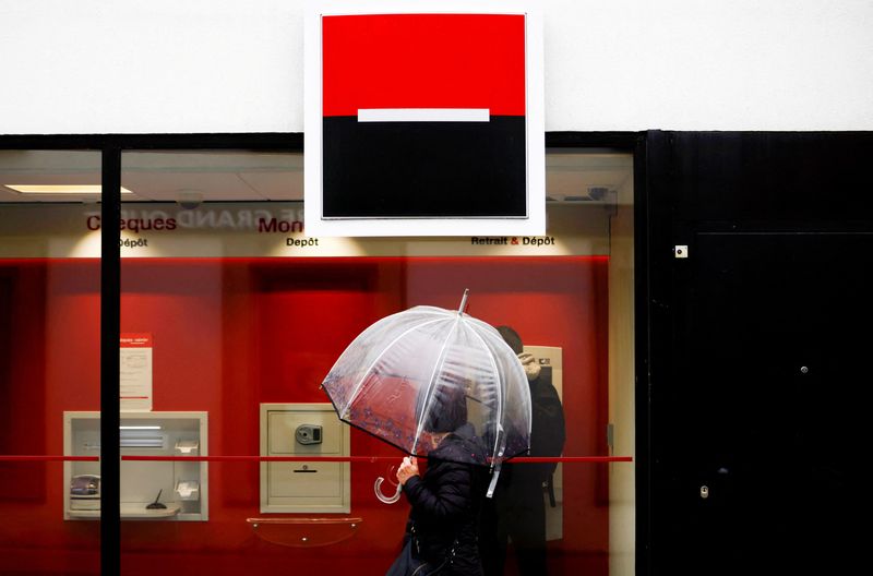 FILE PHOTO: A person holds an umbrella as the logo of French Bank Societe Generale is seen outside a bank building in Saint-Sebastien-sur-Loire near Nantes