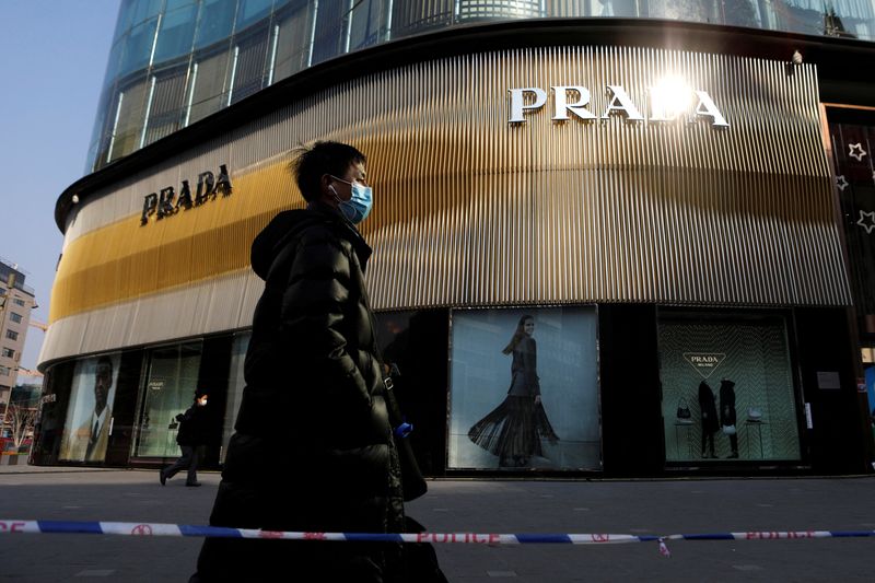 FILE PHOTO: Man wearing a face mask walks past a store of Italian luxury brand Prada on a shopping street in Beijing