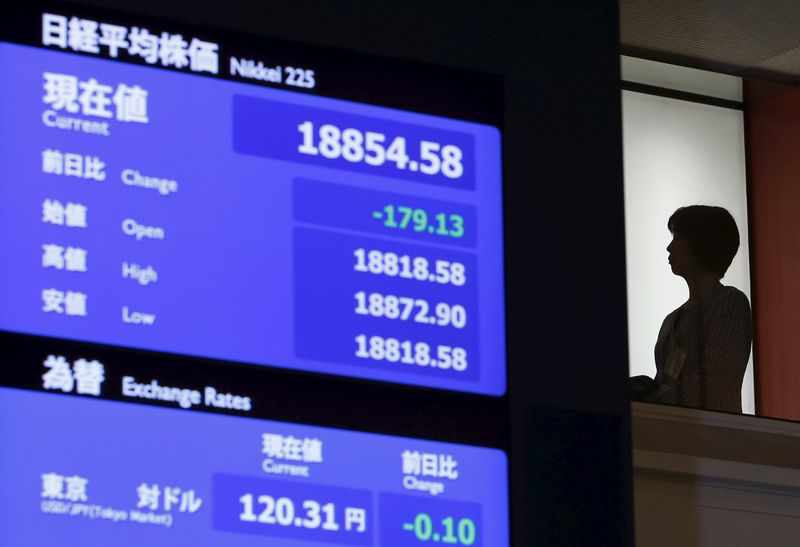 A woman stands near an electronic board at the Tokyo Stock Exchange