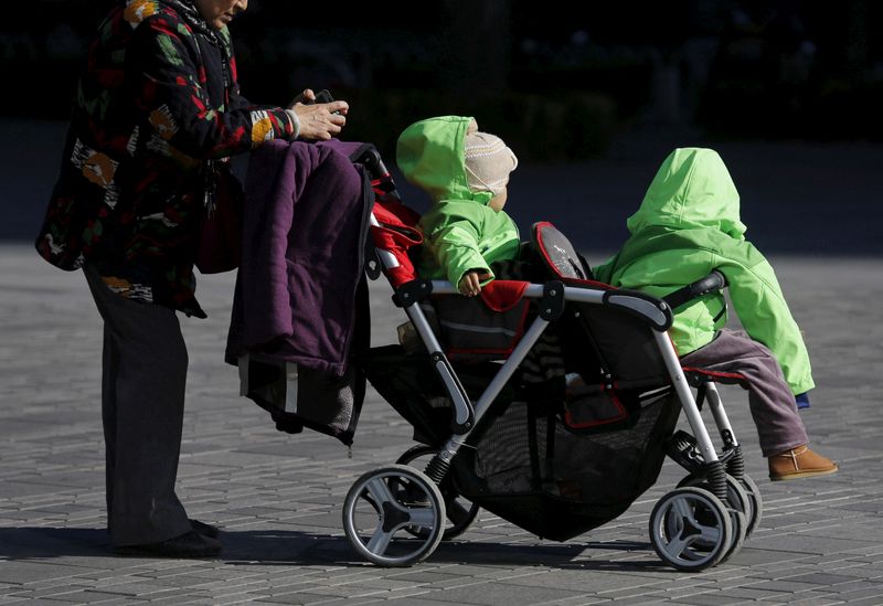 FILE PHOTO: An elderly woman pushes two babies in a stroller in Beijing