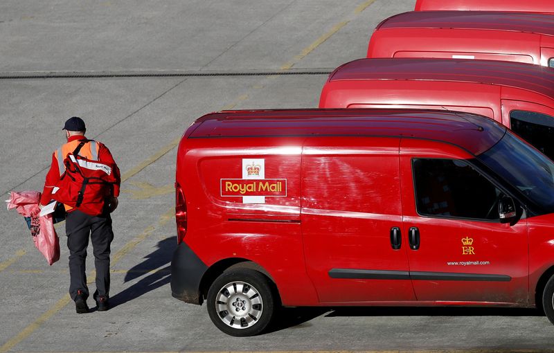 FILE PHOTO: A postal worker carries mail bags from a van at a Royal Mail sorting office in Altrincham northern England