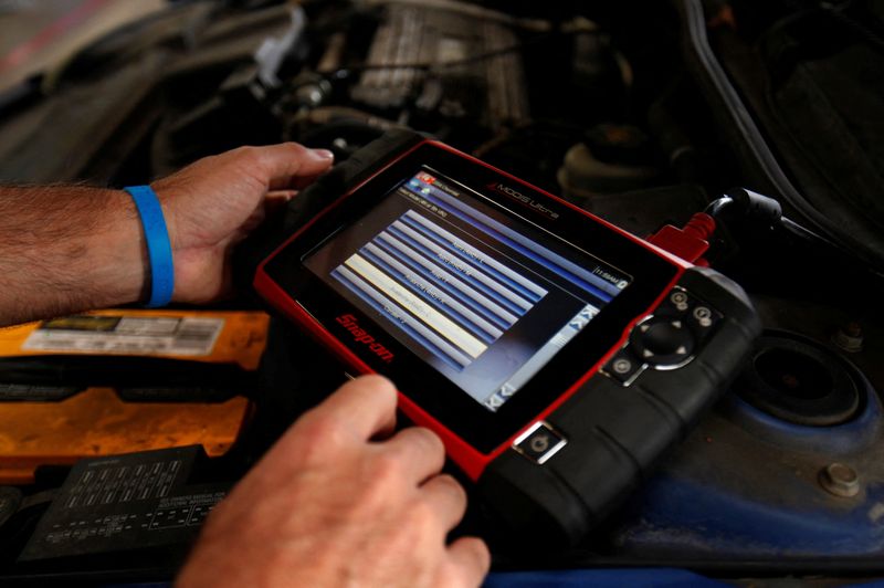 FILE PHOTO: A mechanic uses a hand held computer to try to diagnose a vehicle in for repair at his garage in San Diego