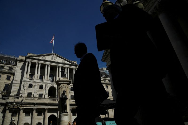 FILE PHOTO: Workers are silhouetted as they walk past the Bank of England, in London