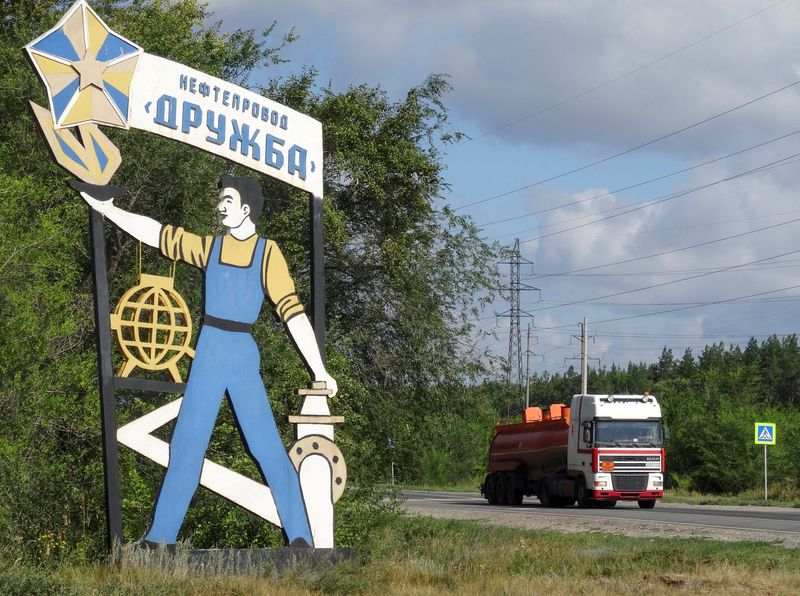 FILE PHOTO: A fuel tank truck drives past a 'Druzhba oil pipeline' signboard near Samara, Russia
