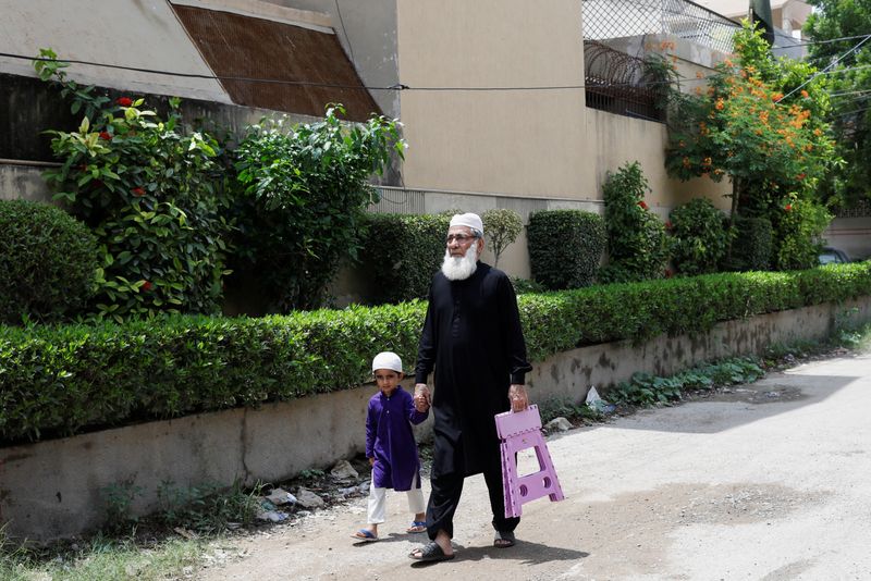 Ali Hasan Baqai, whose family was divided by the partition of the subcontinent in 1947, walks with his five year-old grandson Moosa, as they head to a mosque to attend Friday prayers in Karachi