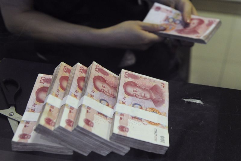 An employee counts Chinese 100 yuan banknotes at a branch of China Merchants Bank in Hefei
