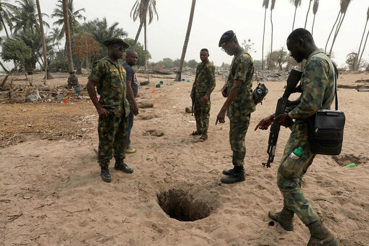 FILE PHOTO: Naval officers inspect an illegally-dug oil well at ilashe in Lagos