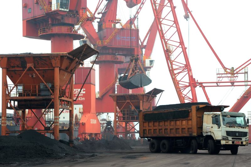 FILE PHOTO: Imported coal is seen lifted by cranes from a coal cargo ship onto a truck at a port in Lianyungang, Jiangsu