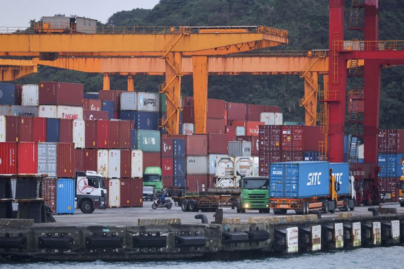 FILE PHOTO: Cargo trucks work inside a container yard, in Keelung