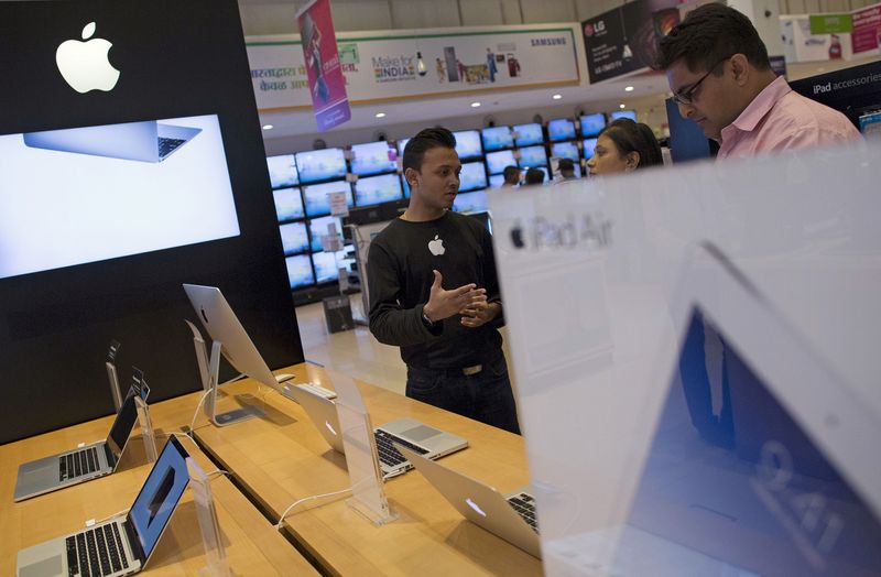 FILE PHOTO: An Apple salesperson speaks to customers at an electronics store in Mumbai