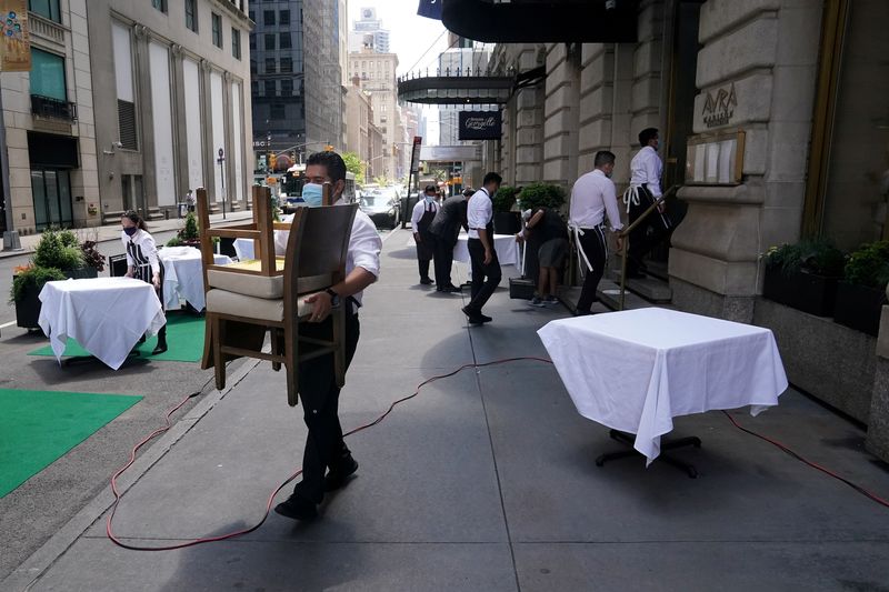 FILE PHOTO: A waiter sets up tables in front of a restaurant on a street on the first day of the phase two re-opening of businesses following the outbreak of the coronavirus disease (COVID-19), in the Manhattan borough of New York City