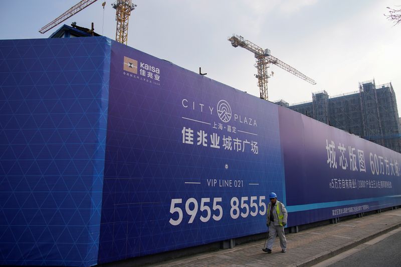 A worker walks past a construction site of Kaisa Group Holdings, in Shanghai