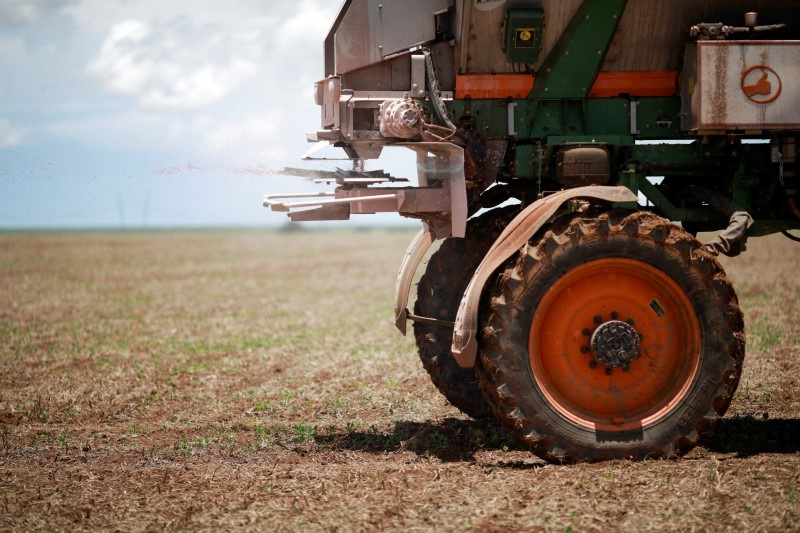 FILE PHOTO: An agricultural worker drives a tractor spreading fertilizer in a soybean field, near Brasilia
