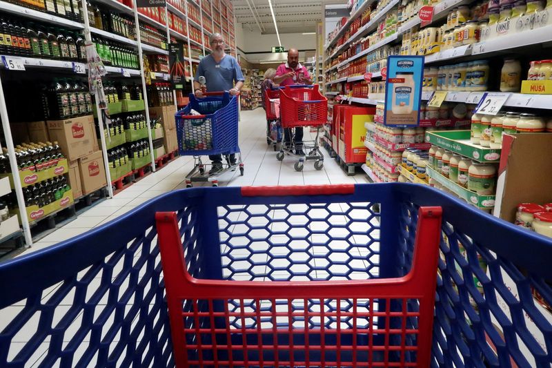 FILE PHOTO: People push a shopping cart in a Carrefour supermarket in Cabrera de Mar