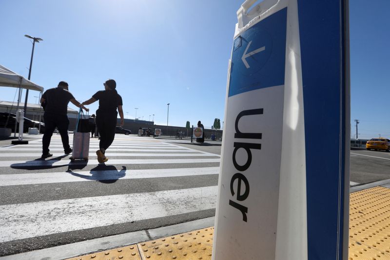 Passengers walk near Uber signage after arriving at Los Angeles International Airport (LAX) in Los Angeles
