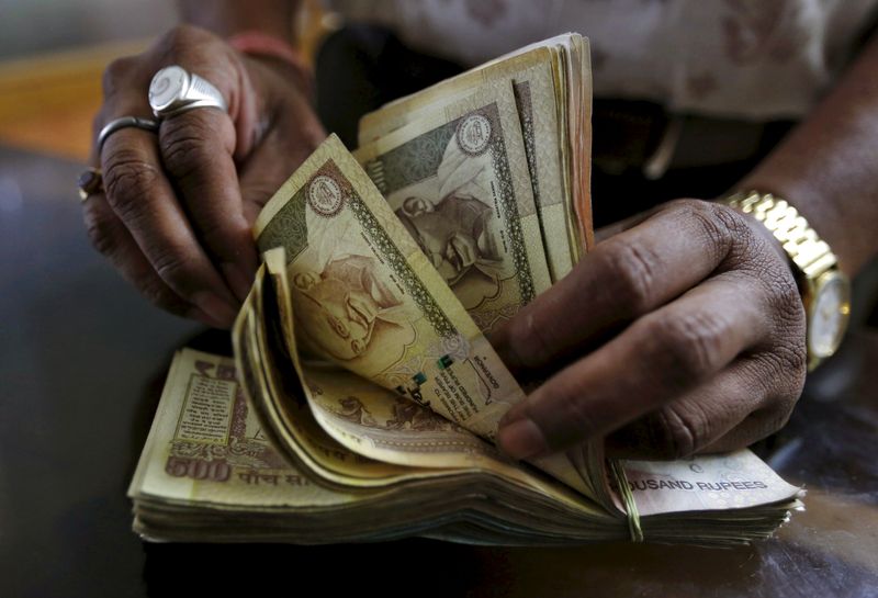FILE PHOTO: A money lender counts Indian rupee currency notes at his shop in Ahmedabad