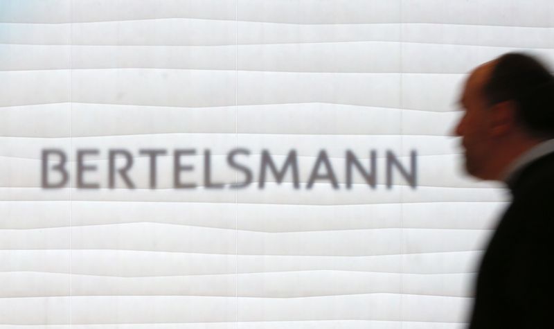 FILE PHOTO: A man is silhouetted in front of the logo of German media group Bertelsmann prior to annual news conference in Berlin