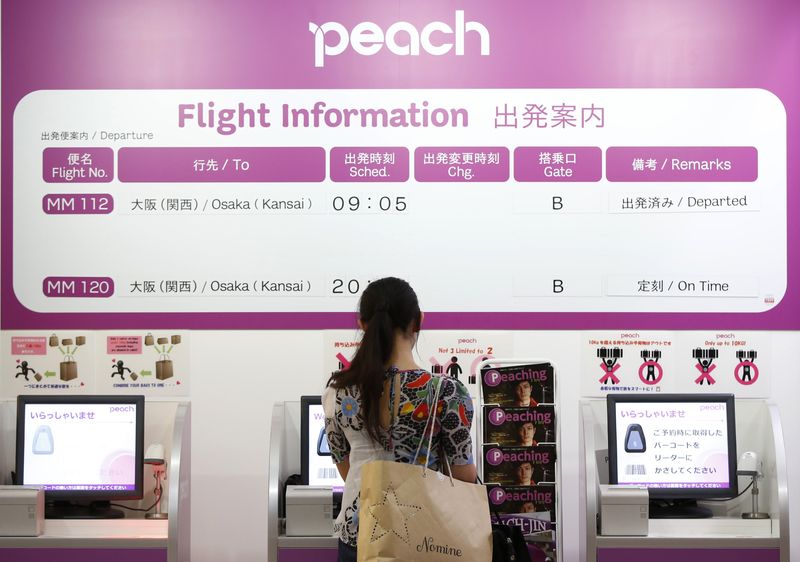 A passenger stands in front of a Peach Aviation's check-in machine at New Tokyo international airport in Narita