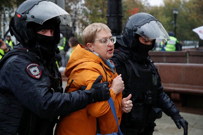 Russian police officers lead away a person during a rally in Moscow