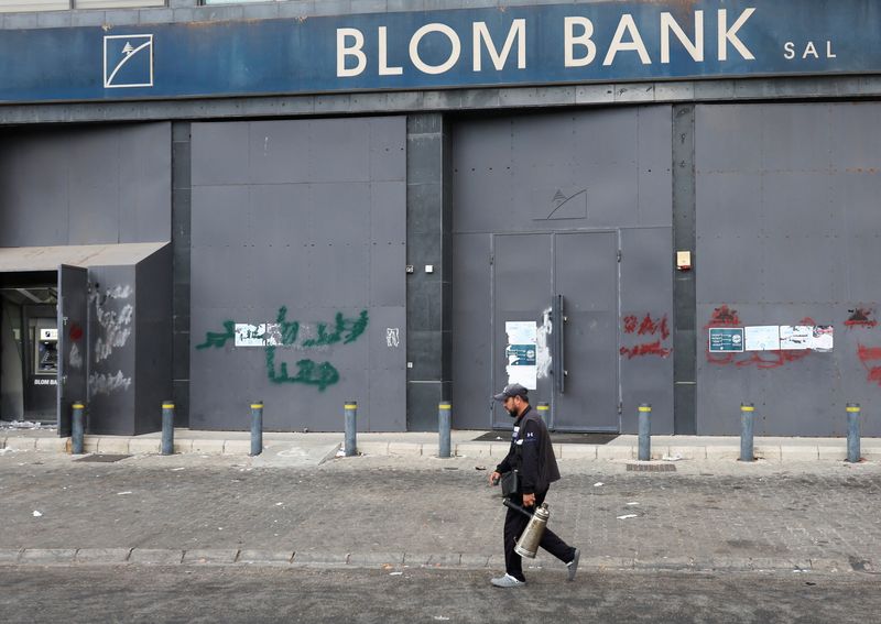 A man walks past a closed Blom Bank branch in Sidon