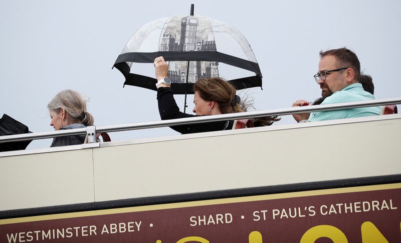 FILE PHOTO: A woman on a tourist bus protects herself from a downpour of rain, in London